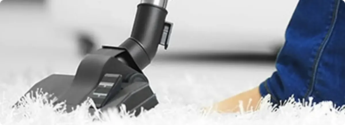 Close-up of a professional vacuuming a white carpet in Spring Valley.